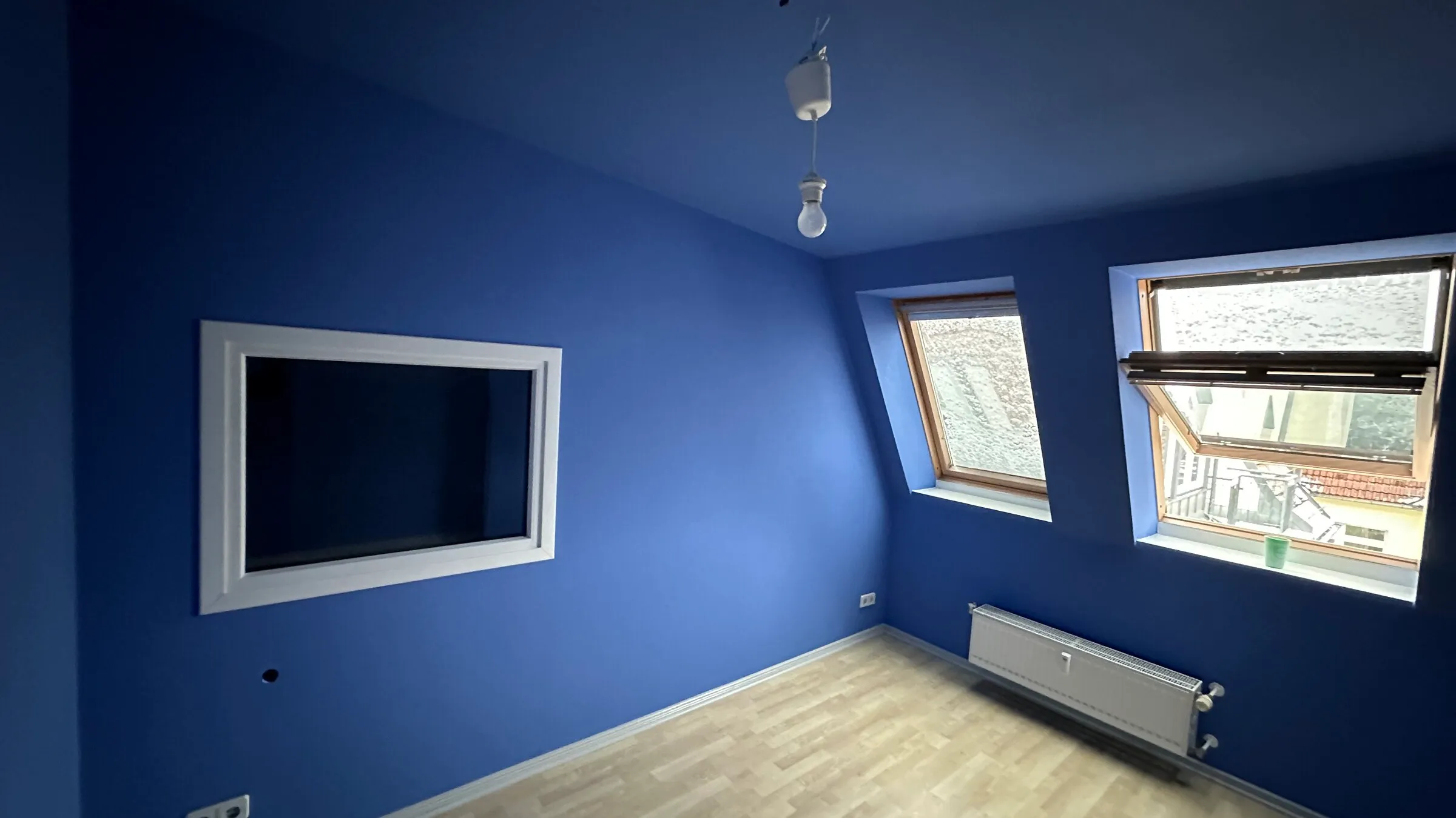 Blue-painted room with a new floor and an opening in the wall