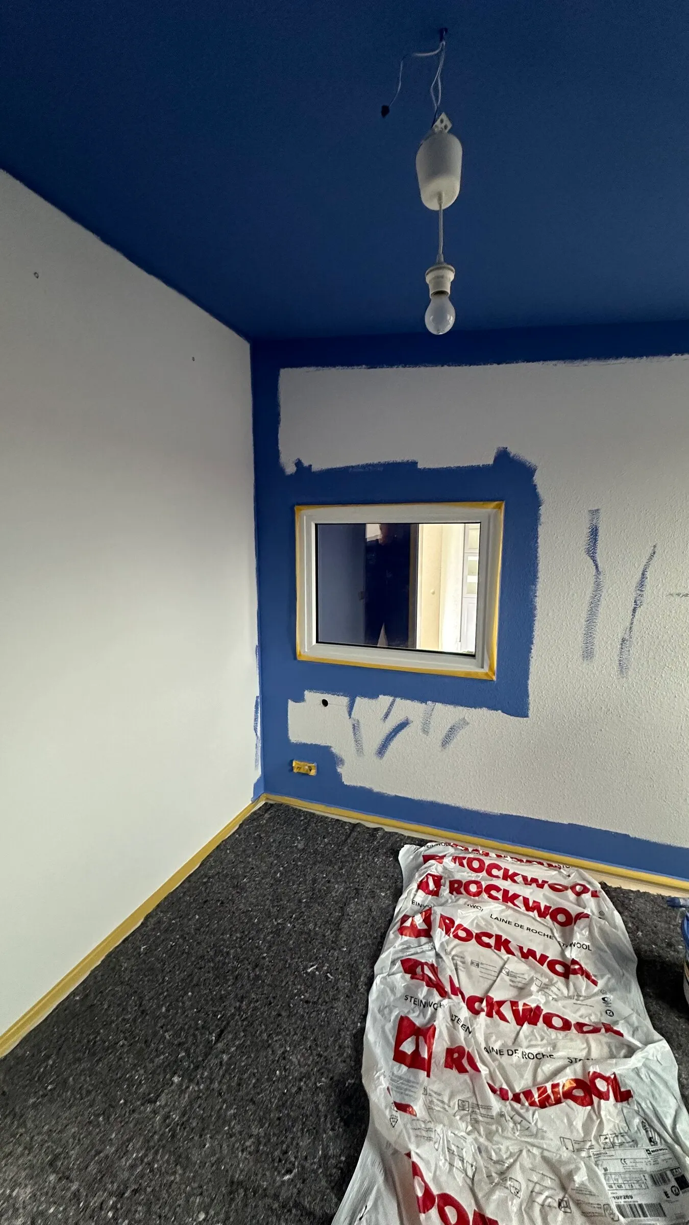 Half-painted room with bags of insulation on the floor