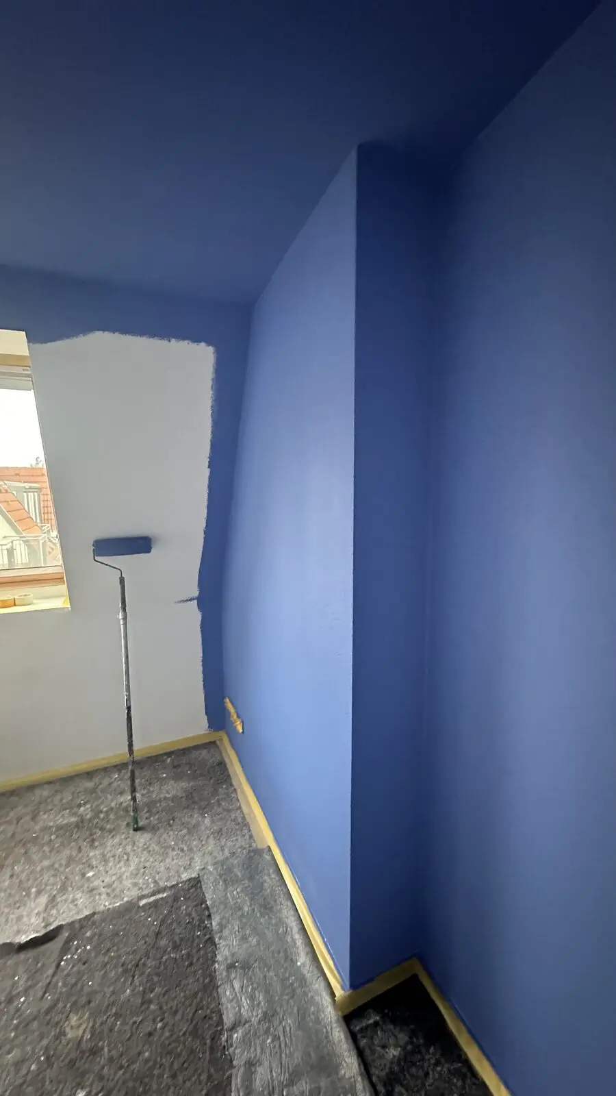 Blue-painted corner, roller on a pole, floor covered