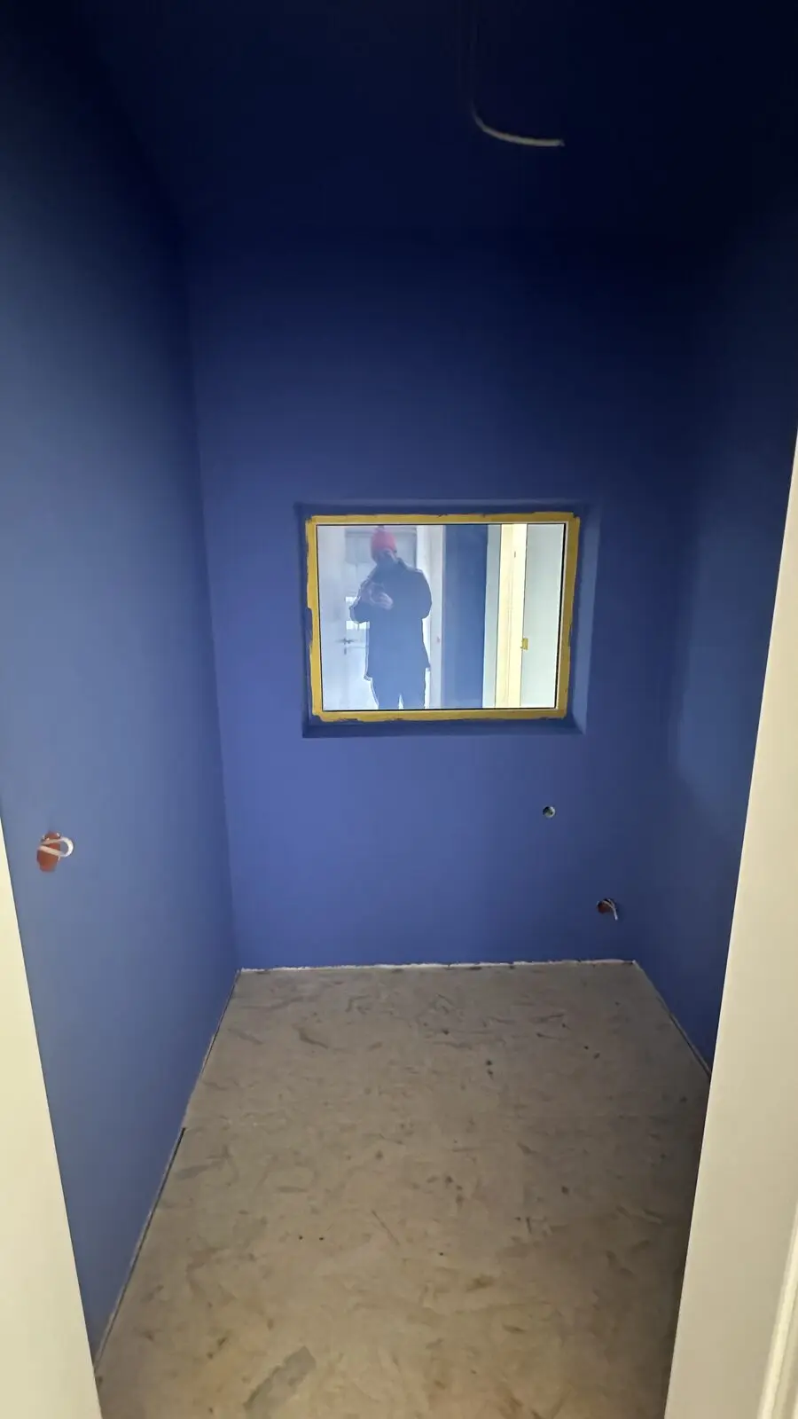 Blue room with a window opening, the floor still bare
