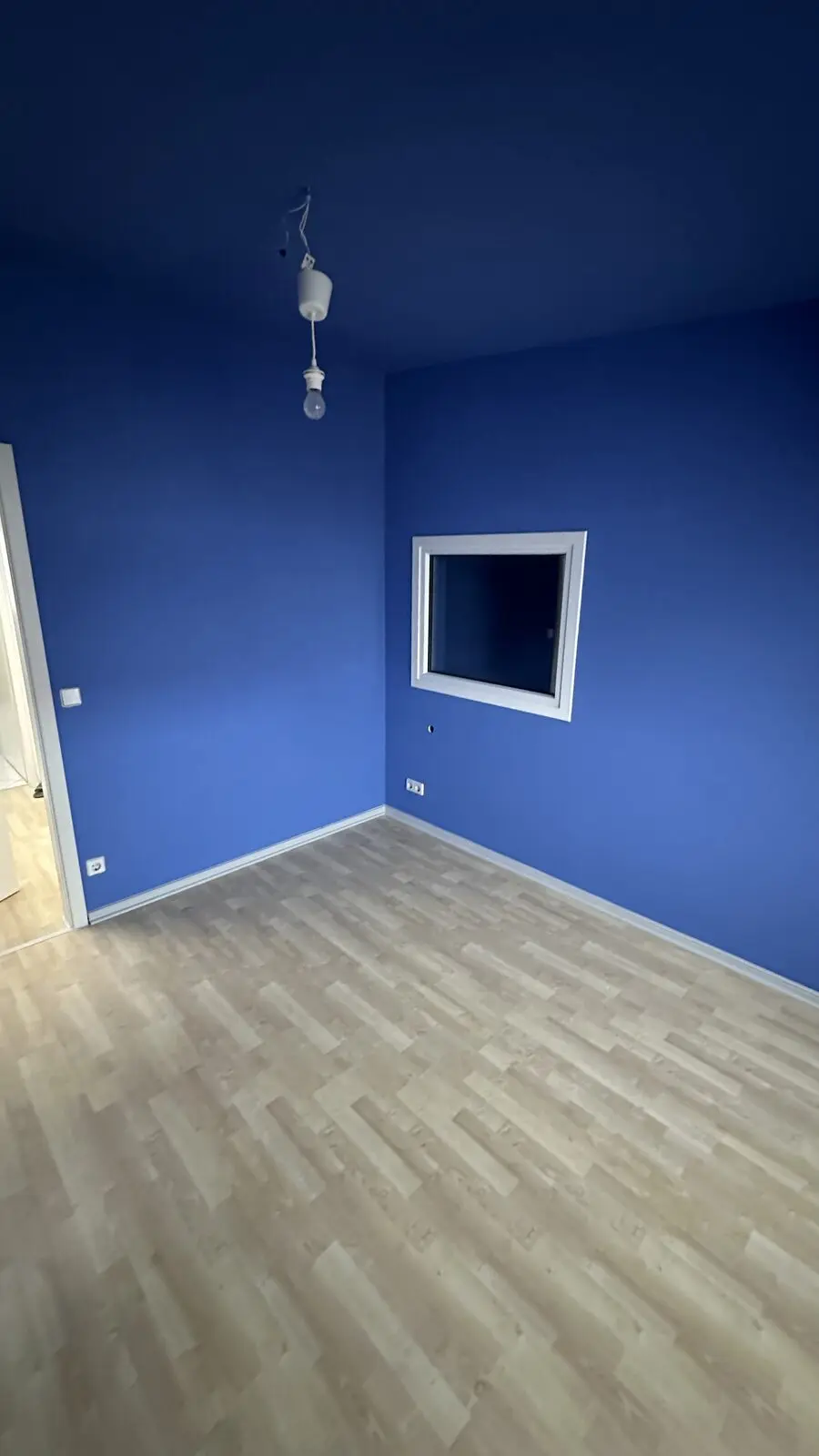 Empty blue room with light laminate flooring