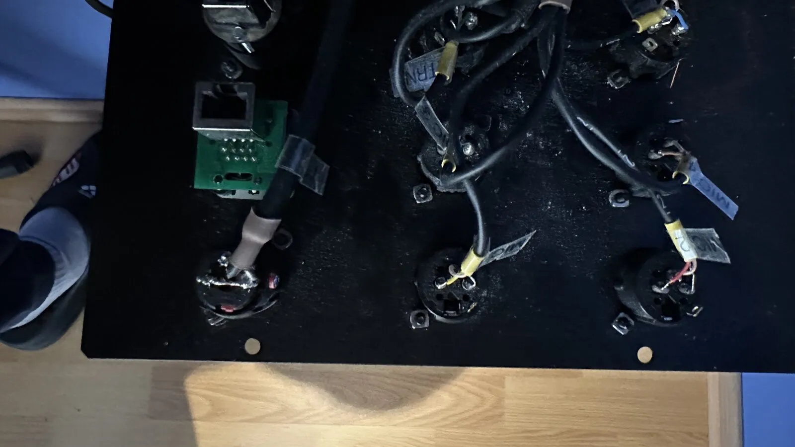 Back of a patch panel with loose sockets and cables on a workbench