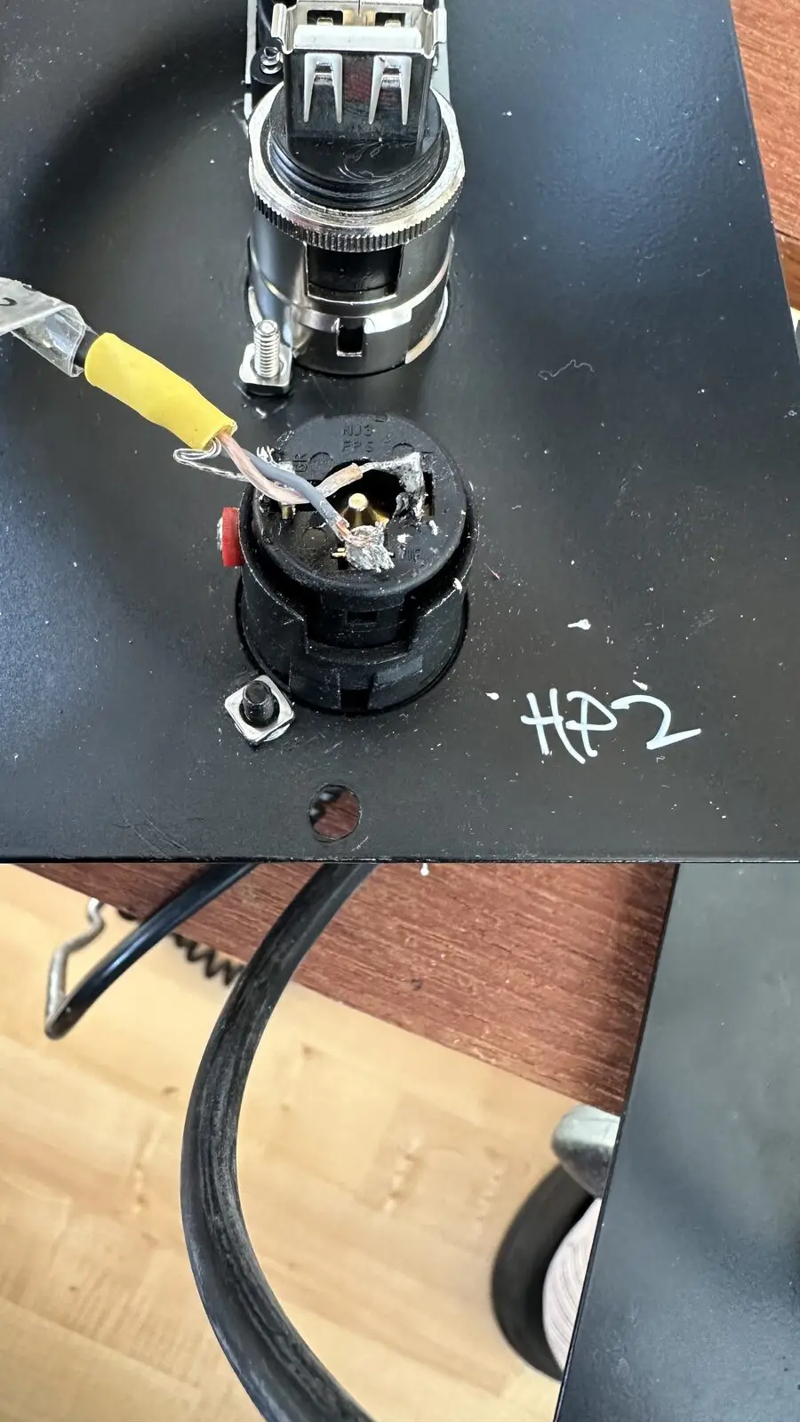 A soldering iron at a socket, a number written next to it in marker