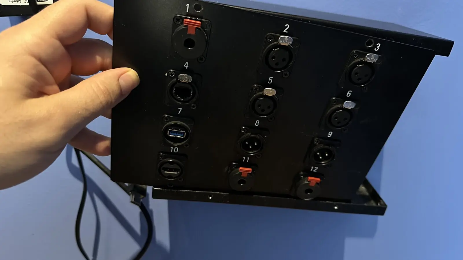 A hand holding the finished panel with twelve numbered sockets