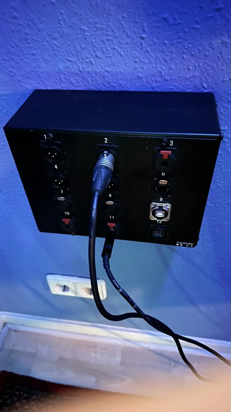 The fitted panel on the blue wall with one cable plugged in