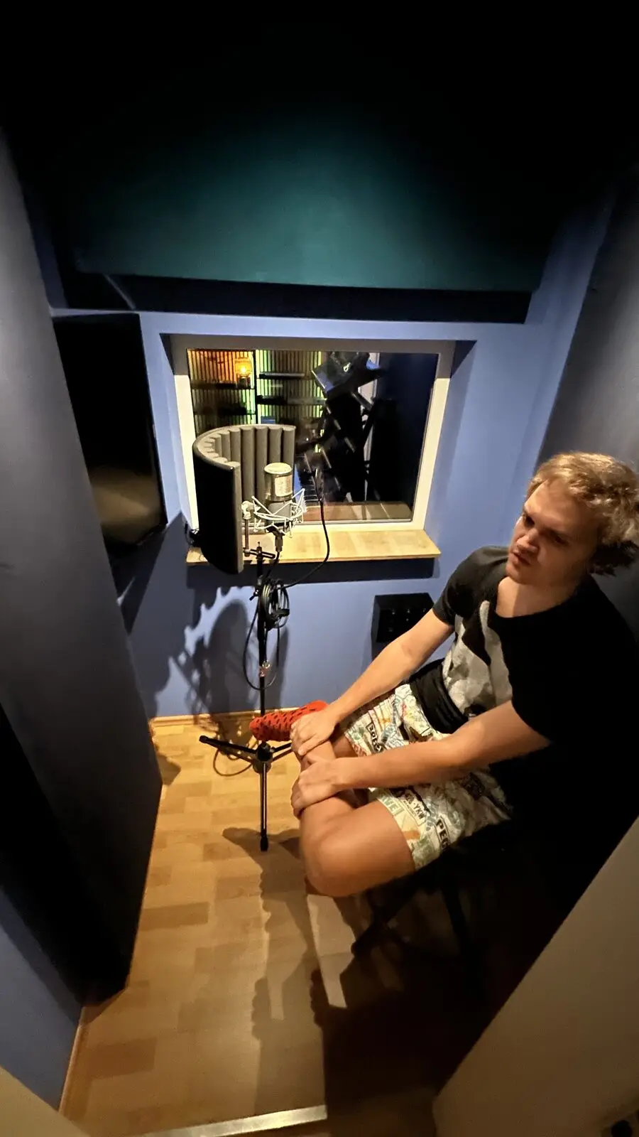 A singer sitting beside the microphone, looking towards the control room