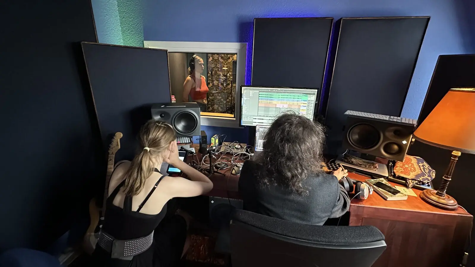 Two people at the desk in front of the monitors during a session