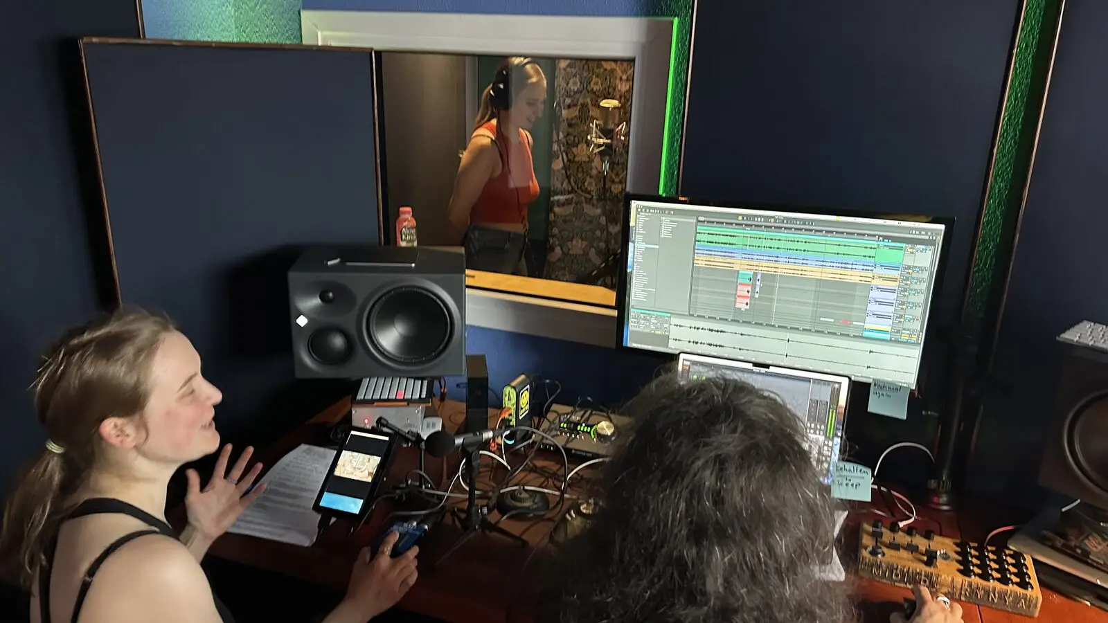Anna and Yura at the desk, the voice artist visible in the booth behind them