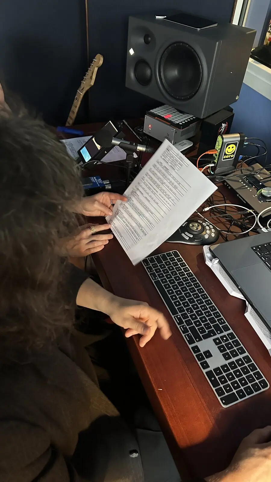 Hands holding a printed sheet above the keyboard at the desk