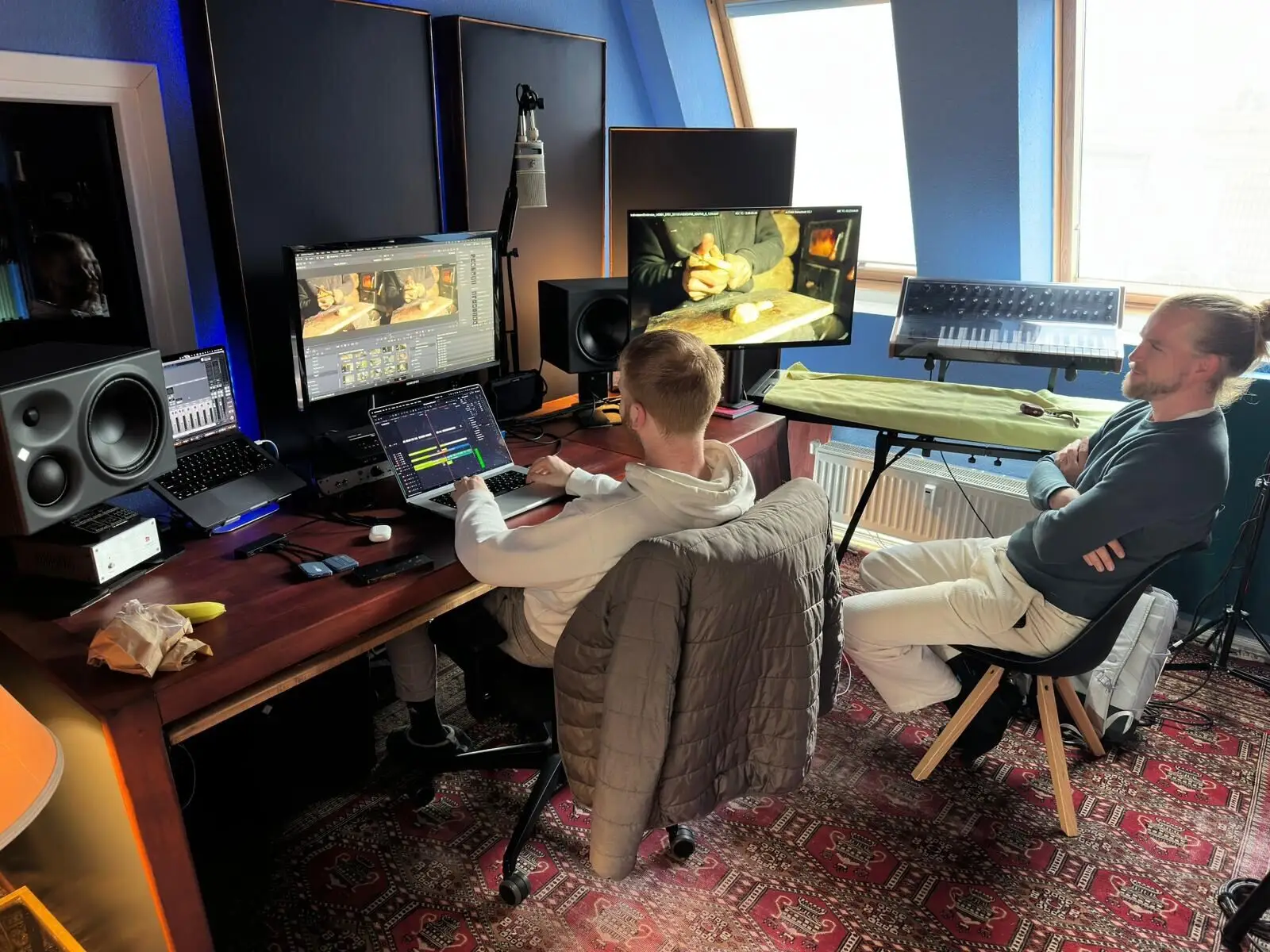 Two at the edit desk: picture on the monitors, synthesizer against the light